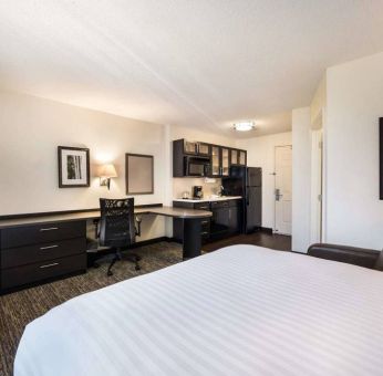 Sonesta Simply Suites Phoenix Tempe double bed guest room, furnished with TV and armchair, plus a workspace desk and chair.