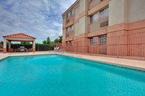 The outdoor pool at Sonesta Simply Suites Phoenix Tempe has sun loungers by the side, and is close to the gazebo and barbecue facilities.