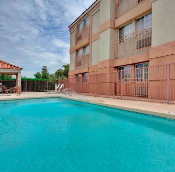 The outdoor pool at Sonesta Simply Suites Phoenix Tempe has sun loungers by the side, and is close to the gazebo and barbecue facilities.