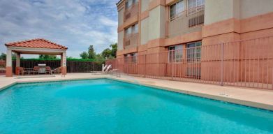 The outdoor pool at Sonesta Simply Suites Phoenix Tempe has sun loungers by the side, and is close to the gazebo and barbecue facilities.