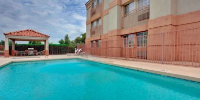 The outdoor pool at Sonesta Simply Suites Phoenix Tempe has sun loungers by the side, and is close to the gazebo and barbecue facilities.