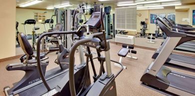 Sonesta Simply Suites Phoenix Tempe’s fitness center has a mirrored wall and a range of exercise equipment.