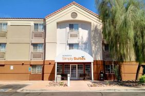 The hotel’s exterior has a pair of benches beneath the covered entranceway, disabled parking spaces nearby, and a towering tree.