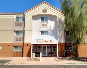 The hotel’s exterior has a pair of benches beneath the covered entranceway, disabled parking spaces nearby, and a towering tree.