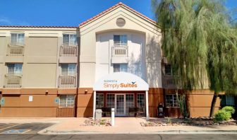 The hotel’s exterior has a pair of benches beneath the covered entranceway, disabled parking spaces nearby, and a towering tree.