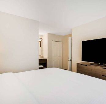 Sonesta ES Suites Denver South - Park Meadows double bed guest room, including bedside lamp and large TV.