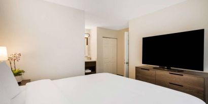 Sonesta ES Suites Denver South - Park Meadows double bed guest room, including bedside lamp and large TV.