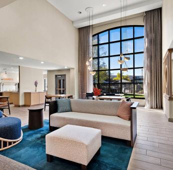 The lobby lounge in Sonesta ES Suites Denver South - Park Meadows has tables and chairs, plus sofa seating, a high ceiling and large windows for plenty of natural light.