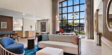 The lobby lounge in Sonesta ES Suites Denver South - Park Meadows has tables and chairs, plus sofa seating, a high ceiling and large windows for plenty of natural light.