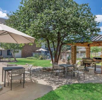 Sonesta ES Suites Denver South - Park Meadows’ patio includes shaded tables and chairs, trees, and a gazebo with barbecue facilities.