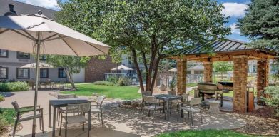 Sonesta ES Suites Denver South - Park Meadows’ patio includes shaded tables and chairs, trees, and a gazebo with barbecue facilities.