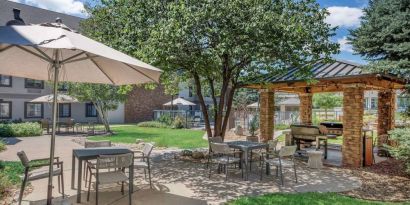 Sonesta ES Suites Denver South - Park Meadows’ patio includes shaded tables and chairs, trees, and a gazebo with barbecue facilities.