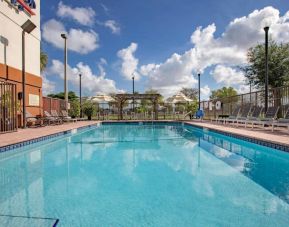 Sonesta Simply Suites Miami Airport Doral’s outdoor pool has sun loungers by the side, and tables and chairs nearby.