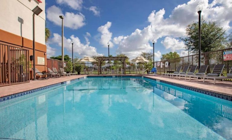 Sonesta Simply Suites Miami Airport Doral’s outdoor pool has sun loungers by the side, and tables and chairs nearby.