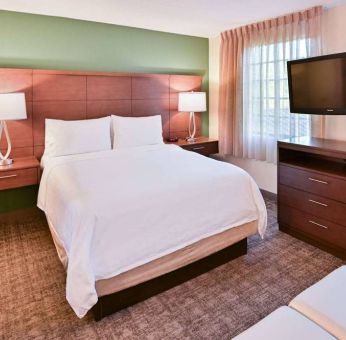 Double bed guest room in Sonesta ES Suites Fort Lauderdale Plantation, featuring bedside lamps, windows, and a large TV.