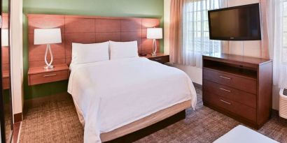 Double bed guest room in Sonesta ES Suites Fort Lauderdale Plantation, featuring bedside lamps, windows, and a large TV.