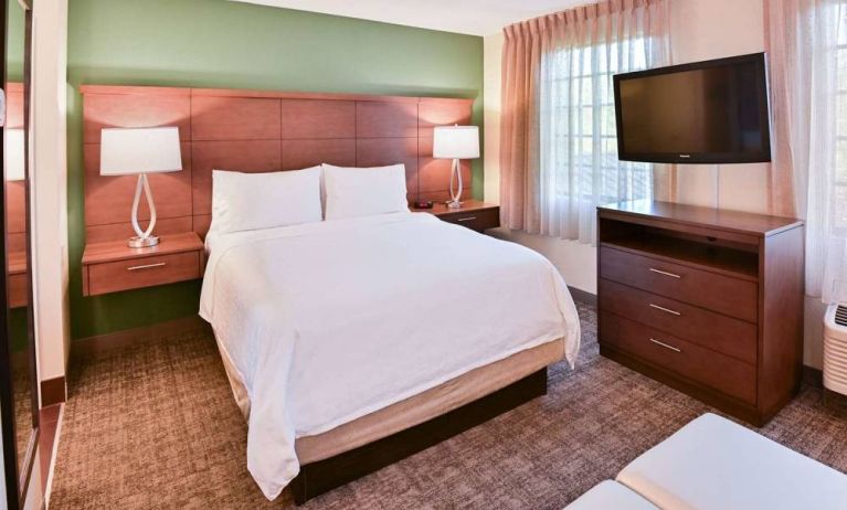 Double bed guest room in Sonesta ES Suites Fort Lauderdale Plantation, featuring bedside lamps, windows, and a large TV.