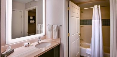 Guest bathroom in Sonesta ES Suites Fort Lauderdale Plantation, with shower-equipped bath, lavatory, mirror, and sink.