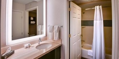 Guest bathroom in Sonesta ES Suites Fort Lauderdale Plantation, with shower-equipped bath, lavatory, mirror, and sink.