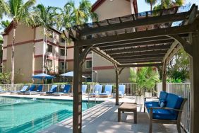 Sonesta ES Suites Fort Lauderdale Plantation’s outdoor pool has sofa seating and a coffee table by the side, alongside a row of sun loungers.