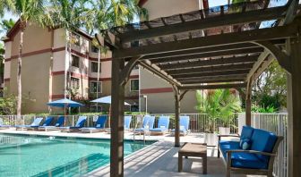 Sonesta ES Suites Fort Lauderdale Plantation’s outdoor pool has sofa seating and a coffee table by the side, alongside a row of sun loungers.