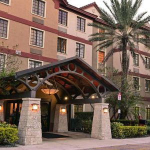 The hotel’s exterior features a covered entrance beside which there’s extensive greenery, including a towering palm tree.