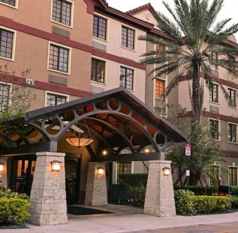 The hotel’s exterior features a covered entrance beside which there’s extensive greenery, including a towering palm tree.