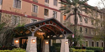 The hotel’s exterior features a covered entrance beside which there’s extensive greenery, including a towering palm tree.