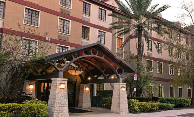 The hotel’s exterior features a covered entrance beside which there’s extensive greenery, including a towering palm tree.