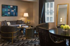 Lounge within a guest room of The Allegro Royal Sonesta Hotel Chicago Loop, including sofa, armchairs, coffee tables, and a window.