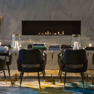 The Allegro Royal Sonesta Hotel Chicago Loop’s lobby lounge includes a table, comfortable seating, and a fireplace.