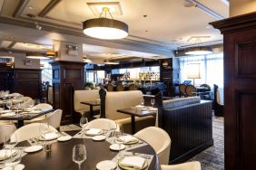 The hotel’s restaurant offers both table and booth seating, with a mix of white seats and dark wood tables, plus a bar.