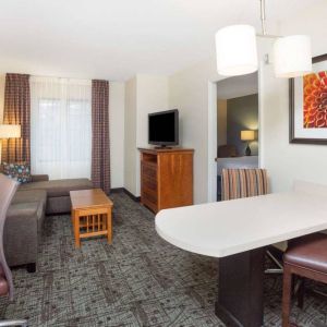 Sonesta ES Suites Atlanta - Perimeter Center double bed guest room, with living area that has a desk and chair, sofa, coffee tables, window, and TV.