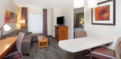 Sonesta ES Suites Atlanta - Perimeter Center double bed guest room, with living area that has a desk and chair, sofa, coffee tables, window, and TV.