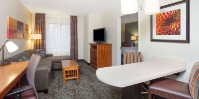 Sonesta ES Suites Atlanta - Perimeter Center double bed guest room, with living area that has a desk and chair, sofa, coffee tables, window, and TV.