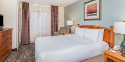 Sonesta ES Suites Atlanta - Perimeter Center double bed guest room, featuring TV, armchair, and window.