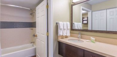 Guest bathroom in Sonesta ES Suites Atlanta - Perimeter Center, with shower and bath, sink and mirror.