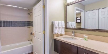 Guest bathroom in Sonesta ES Suites Atlanta - Perimeter Center, with shower and bath, sink and mirror.