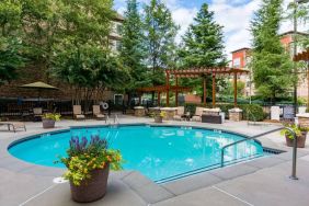 Sonesta ES Suites Atlanta - Perimeter Center’s round outdoor pool has potted plants and sun loungers nearby, with tables and chairs close at hand.