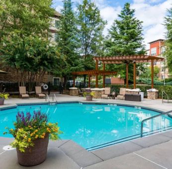 Sonesta ES Suites Atlanta - Perimeter Center’s round outdoor pool has potted plants and sun loungers nearby, with tables and chairs close at hand.