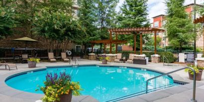 Sonesta ES Suites Atlanta - Perimeter Center’s round outdoor pool has potted plants and sun loungers nearby, with tables and chairs close at hand.