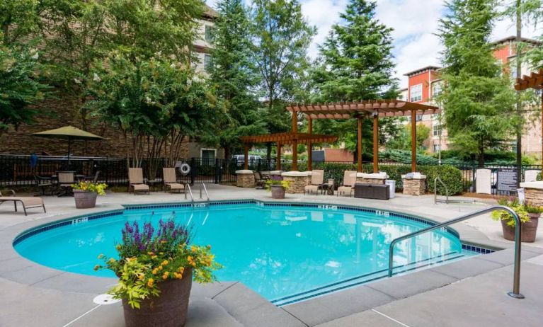 Sonesta ES Suites Atlanta - Perimeter Center’s round outdoor pool has potted plants and sun loungers nearby, with tables and chairs close at hand.