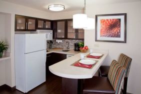 Sonesta ES Suites Atlanta Alpharetta Avalon guest room kitchen, including fridge-freezer, microwave, and kitchen table with two chairs.