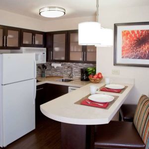 Sonesta ES Suites Atlanta Alpharetta Avalon guest room kitchen, including fridge-freezer, microwave, and kitchen table with two chairs.