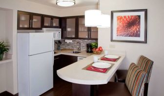 Sonesta ES Suites Atlanta Alpharetta Avalon guest room kitchen, including fridge-freezer, microwave, and kitchen table with two chairs.