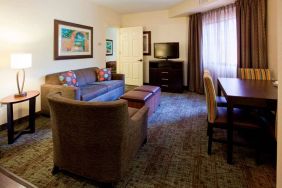 Sonesta ES Suites Atlanta Alpharetta Avalon guest room living area, furnished with sofa, armchair, table and chairs, and a TV.