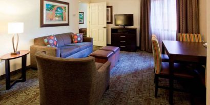 Sonesta ES Suites Atlanta Alpharetta Avalon guest room living area, furnished with sofa, armchair, table and chairs, and a TV.