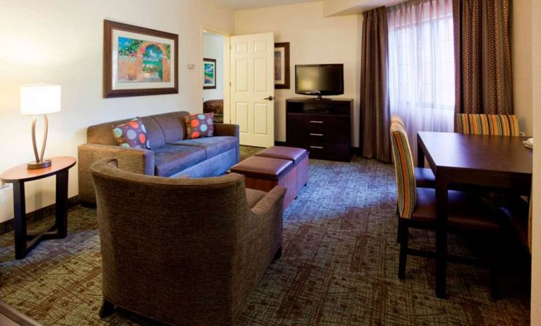 Sonesta ES Suites Atlanta Alpharetta Avalon guest room living area, furnished with sofa, armchair, table and chairs, and a TV.