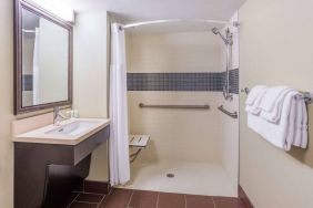 Guest bathroom in Sonesta ES Suites Atlanta Alpharetta Avalon featuring shower with curtain, mirror, and sink.