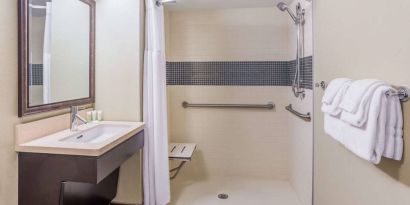 Guest bathroom in Sonesta ES Suites Atlanta Alpharetta Avalon featuring shower with curtain, mirror, and sink.